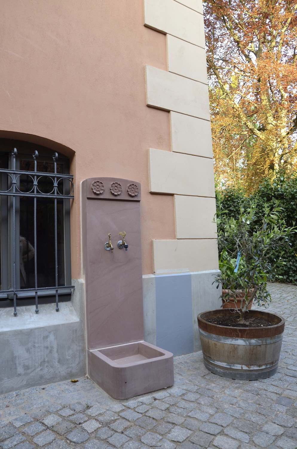 Potsdam: Kleiner Wandbrunnen aus rotem schlesischem Sandstein. Architekturelemente und Ornamente (Rosetten) vom Haus teils aufgenommen. Maßgeschneiderte Steinmetzarbeit. Potsdam: Kleiner Wandbrunnen aus rotem schlesischem Sandstein. Architekturelemente und Ornamente (Rosetten) vom Haus teils aufgenommen. Maßgeschneiderte Steinmetzarbeit.